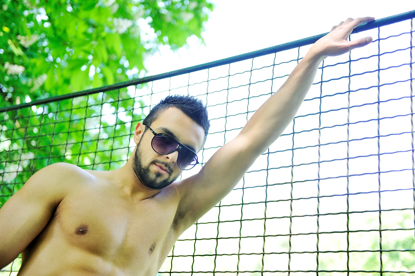 Portrait of a beautiful young muscular man leaning against a fence