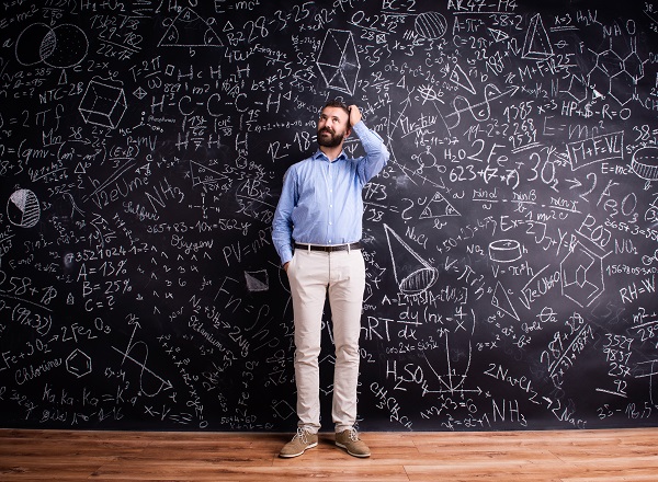 Hipster teacher against big blackboard with mathematical symbols